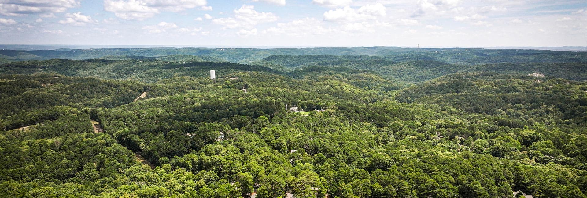 Aerial view of lush green hills under a partly cloudy sky.