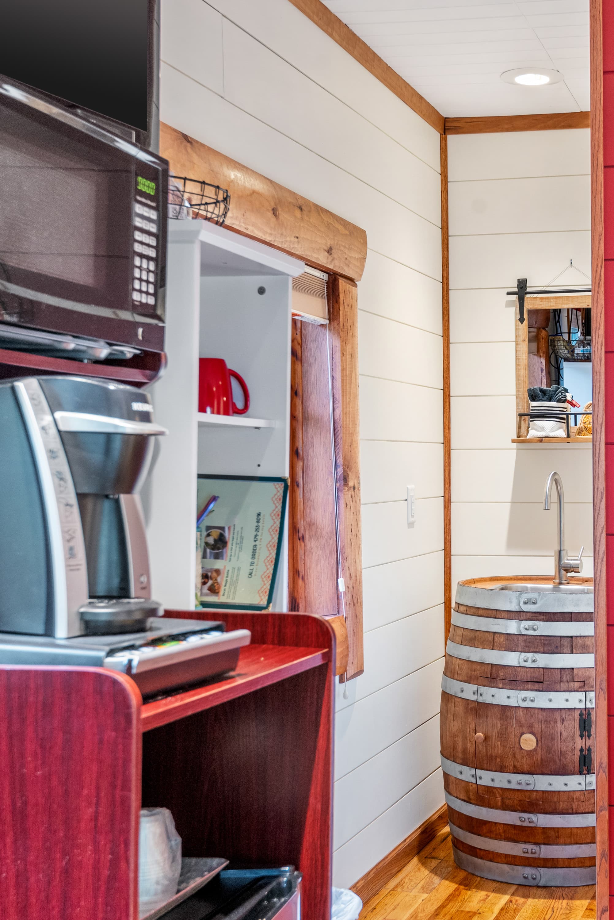 A wet bar with a microwave, coffee maker, and mini-fridge. A doorway leads to a bathroom with a rustic barrel sink.