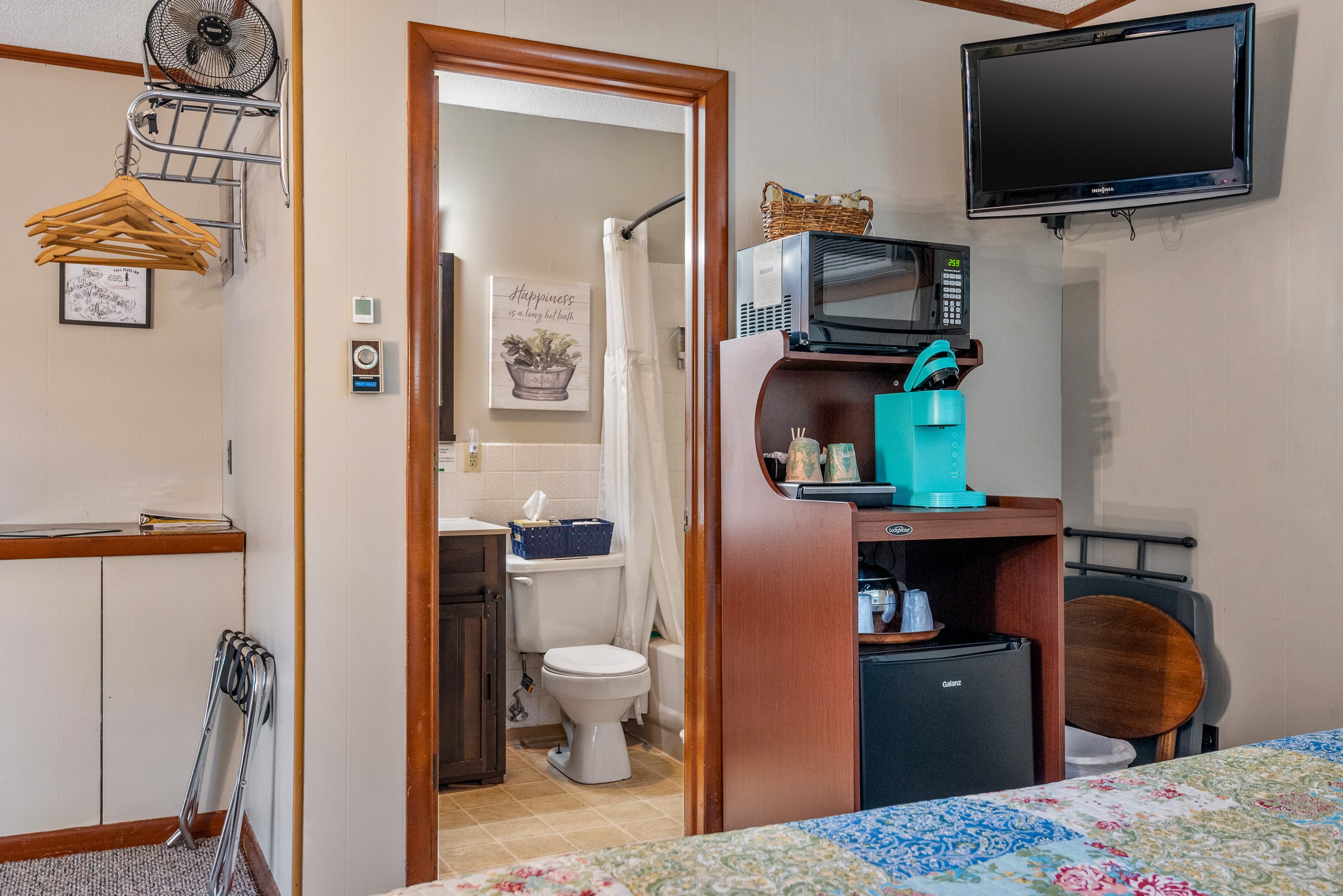 A bedroom with a microwave, a coffee maker, and a mini-fridge. The doorway on the right leads to a small bathroom.