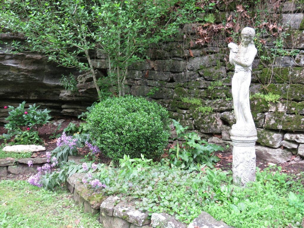Outside Laundry spring white statue surrounded by greenery and flowers