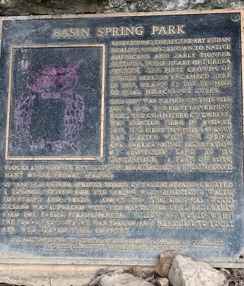 A weathered plaque detailing the history and significance of Basin Spring Park.