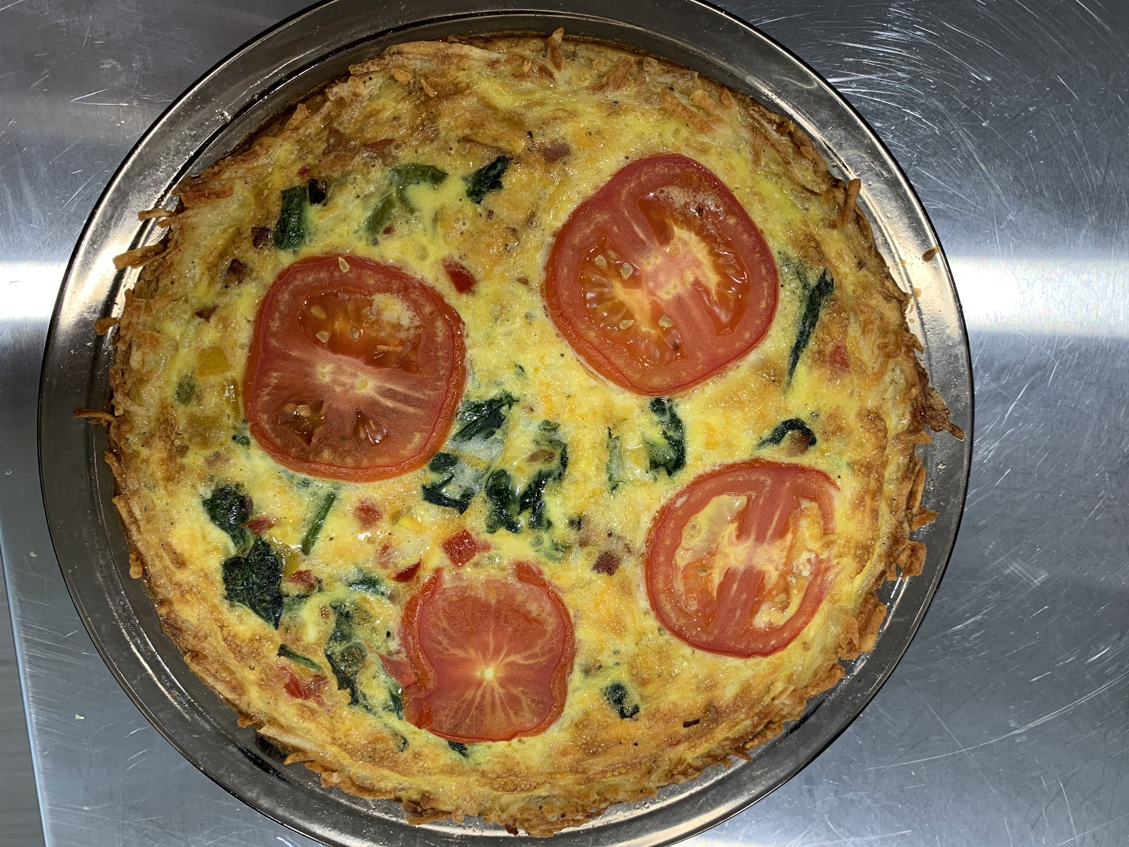 A savory frittata topped with sliced tomatoes and mixed vegetables.