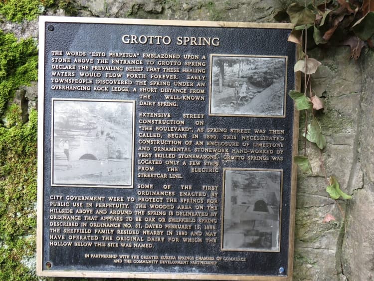 A historical plaque describing Grotto Spring, detailing its significance and the surrounding area's development.