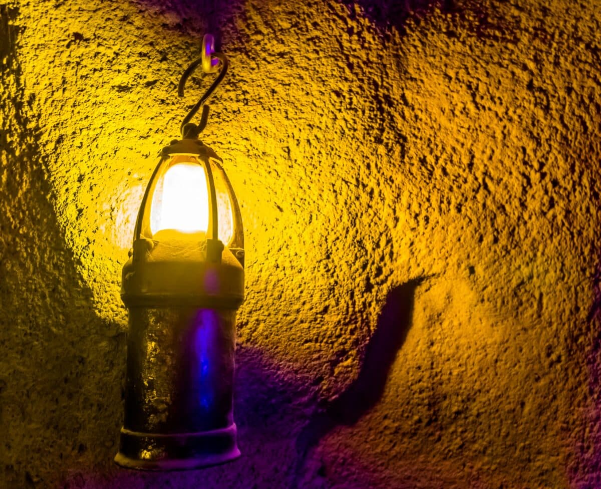 A vintage lantern casts a warm glow on a textured wall.