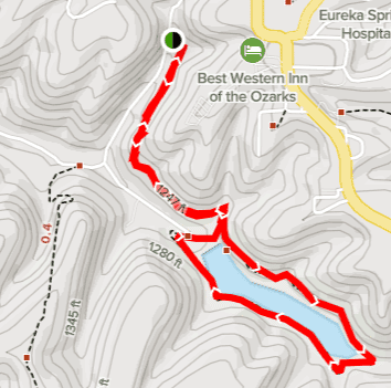 Map showing a hiking trail marked in red, winding around a lake with elevation contours in the background.