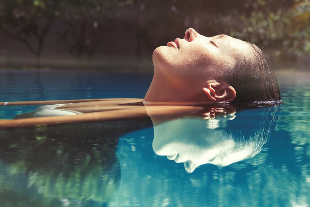 woman floating on her back in a swimming pool