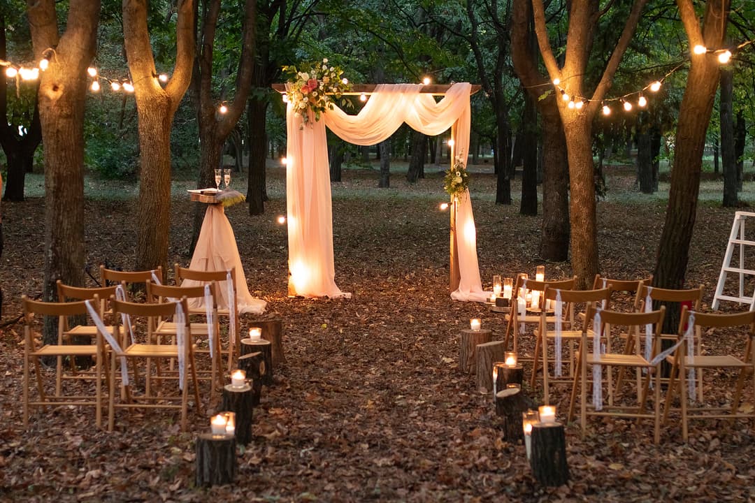 Nighttime formal wedding decor of lighted drapes flowers and chairs